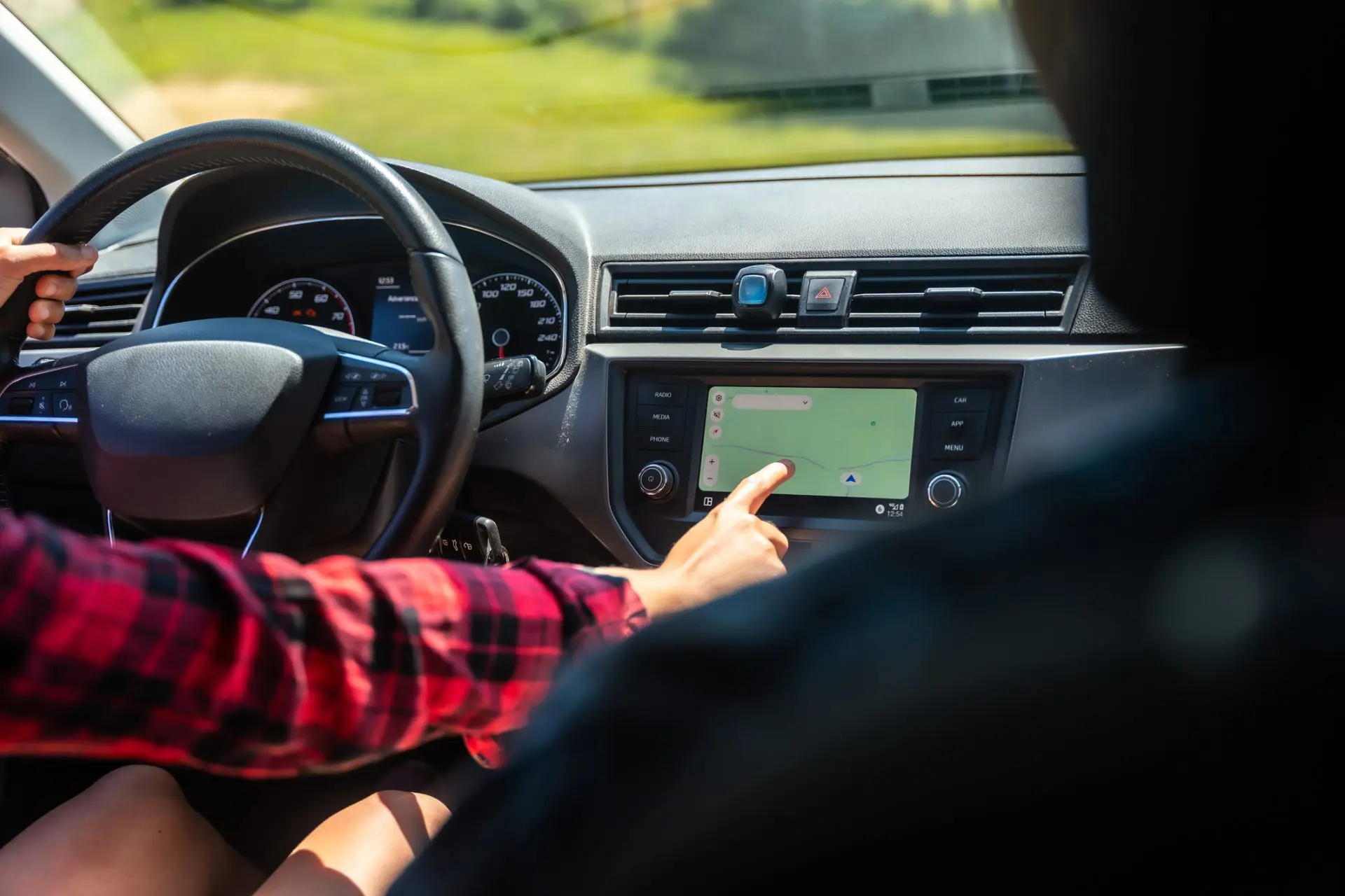 personne au volant qui clique sur l'écran de bord de sa voiture pour activer le GPS