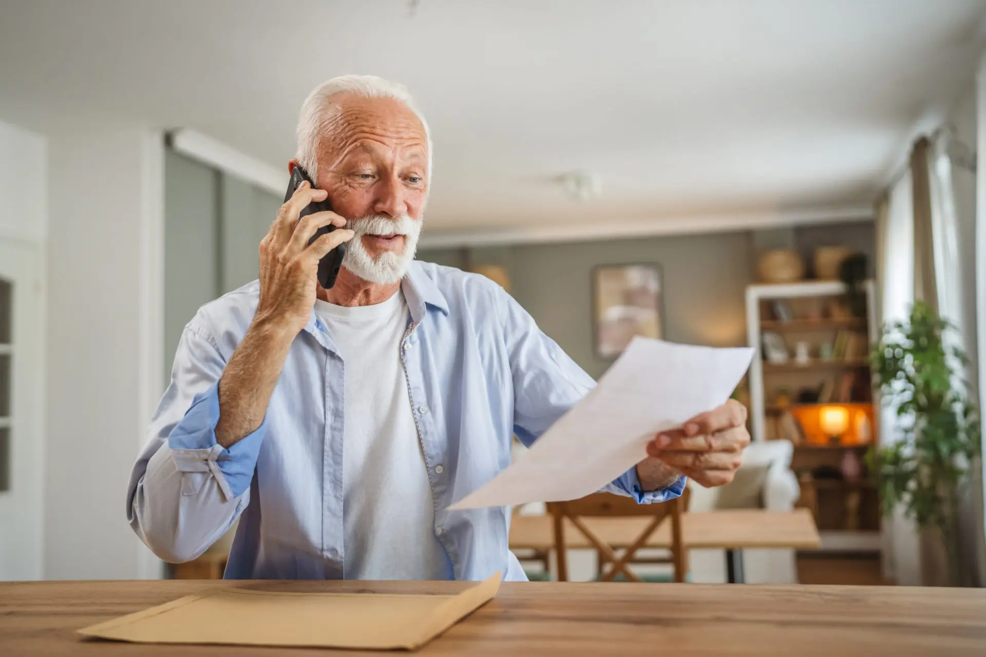 Un homme âgé s’assoit à la maison pour passer un appel téléphonique