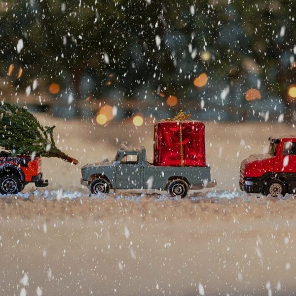 trois petites voitures sous la neige avec des décorations de Noël
