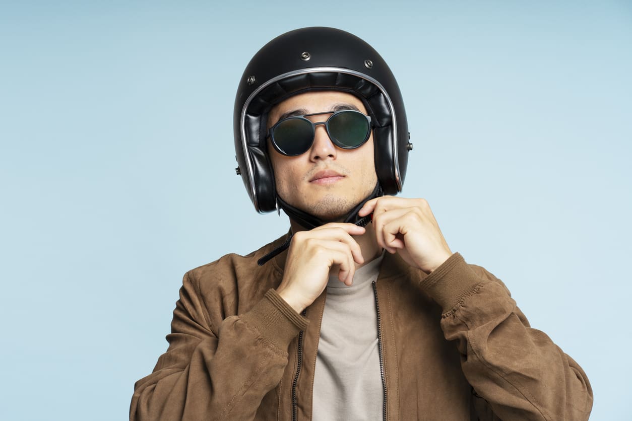 Homme mettant un casque pour faire de la moto avec un fond bleu