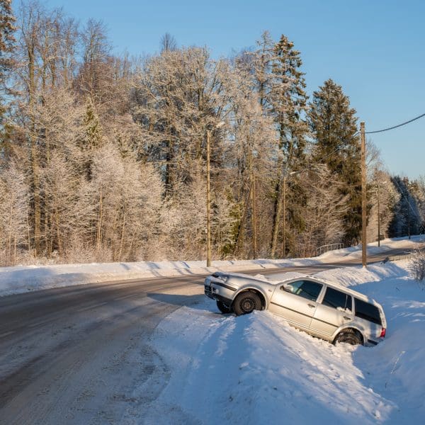 voiture accidentée dans un petit fossé sur une route enneigée