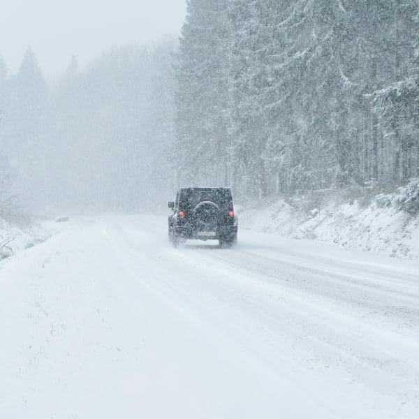 Pick-up qui roule sur une route enneigée avec des arbres autour