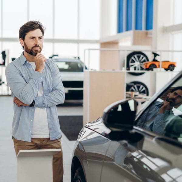 Le client qui choisit d’acheter une nouvelle voiture dans la salle d’exposition de la concession