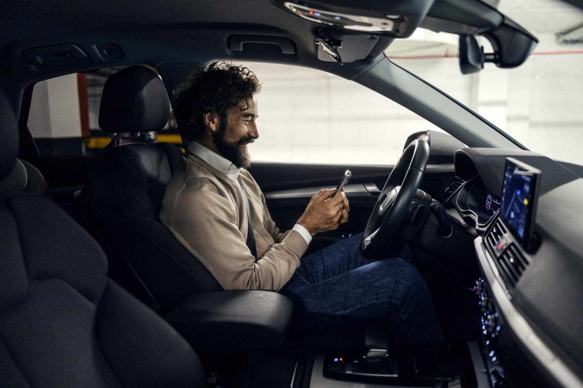 Homme souriant et envoyant des SMS à l’aide d’un smartphone dans la voiture